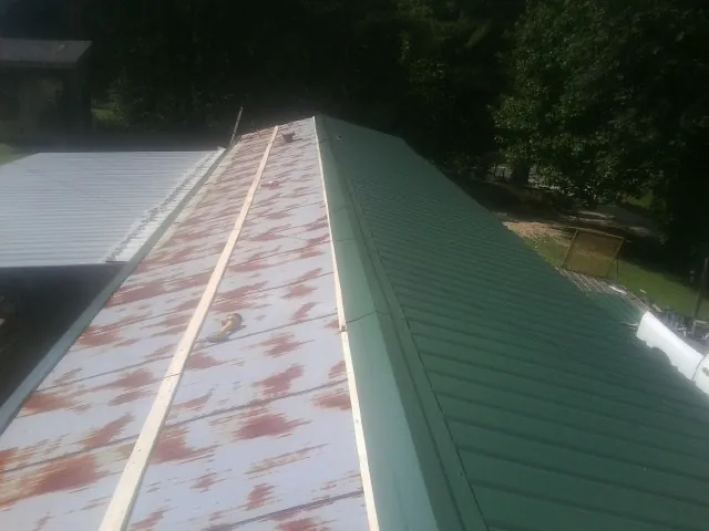 Old rusted panels beside newly installed green metal roofing — Wind Damage Roof Repair by Roofing Brothers in Fairview