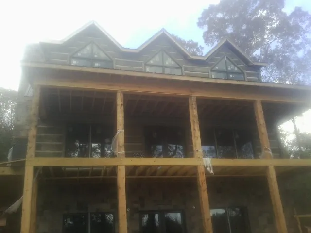 Dormers and porch framing on a large log home under construction — Roof Coating work by our crew in Fairview